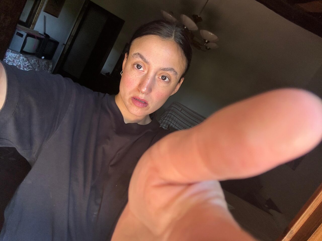Nahaufnahme einer Person, die mit ausgestrecktem Arm ein Selfie macht, der Finger verdeckt teilweise die Kamera.